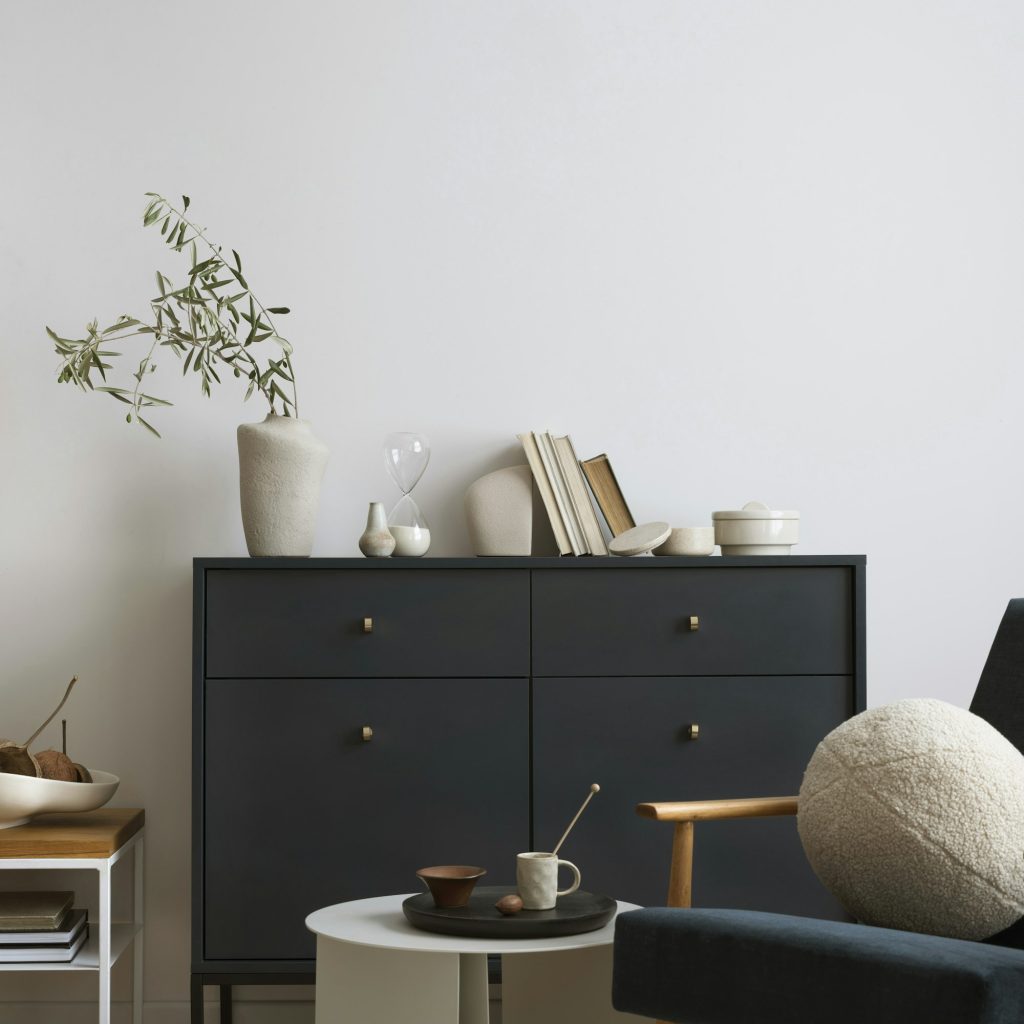 Creative composition of living room interior with navy blue commode, velvet armchair,